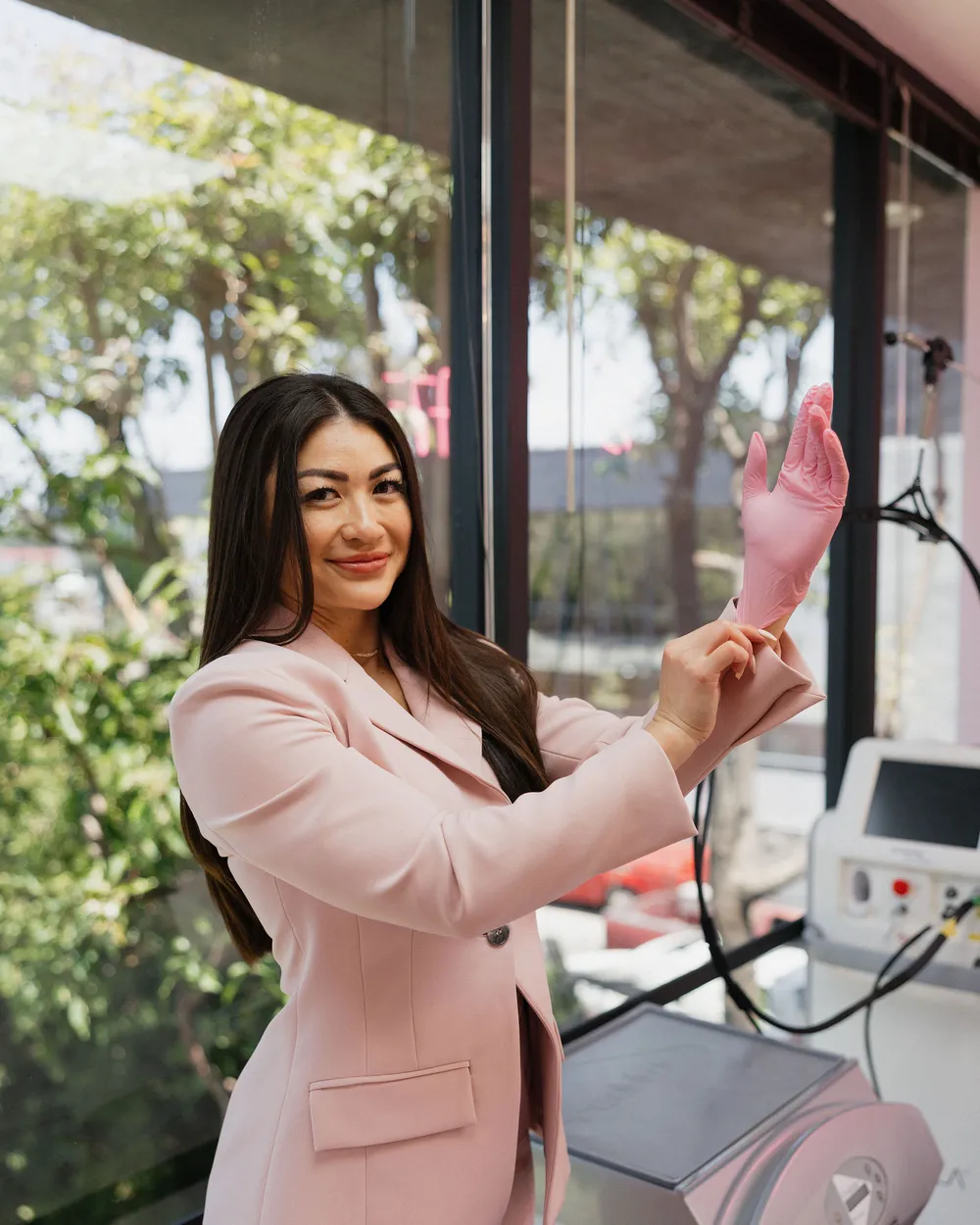 Leslie in a blush blazer, pulling on a pink glove beside the Candela