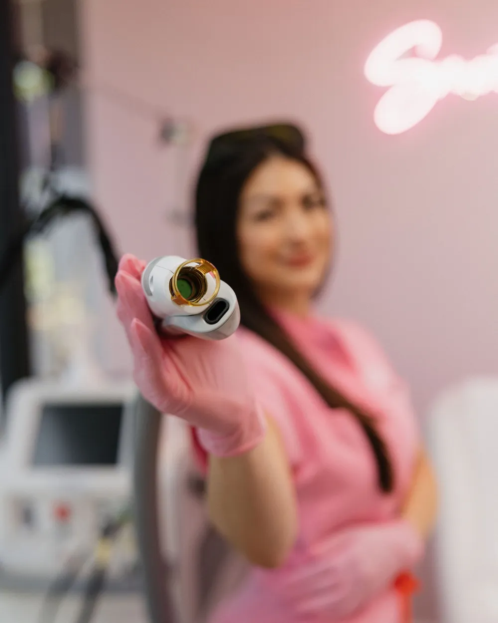 Close-up of the Candela handpiece in Leslie’s pink-gloved hand